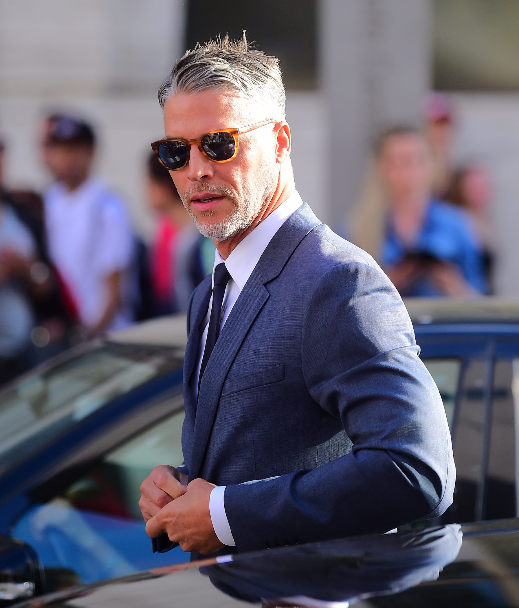 Bryan Randall getting out of a car wearing a suit and sunglasses
