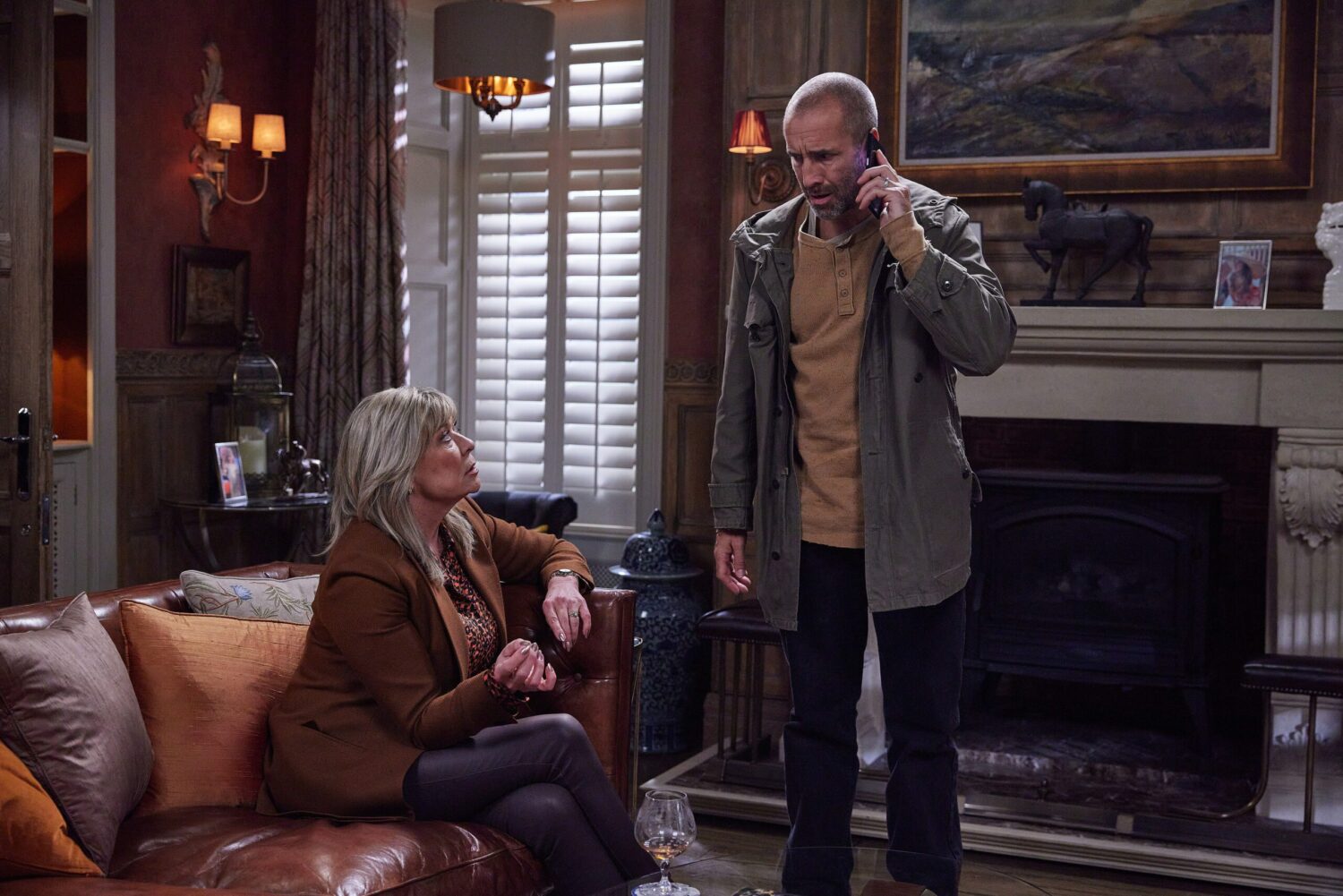 Sam on the phone while Kim looks on in Emmerdale