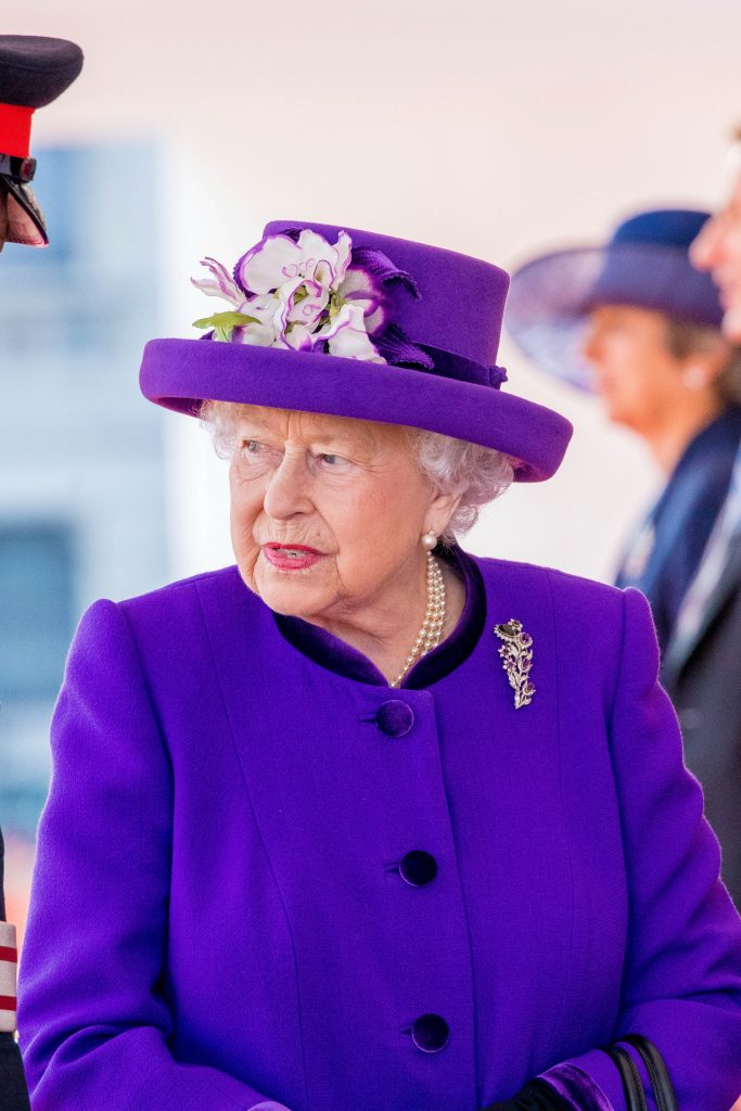 Queen Elizabeth II wears a purple hat and jacket