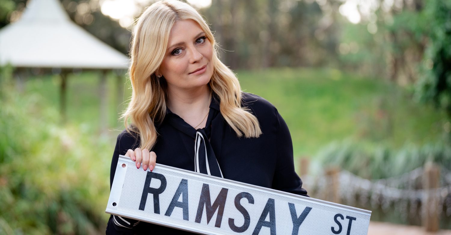 Neighbours' Reece Sinclair holding up the Ramsay St sign