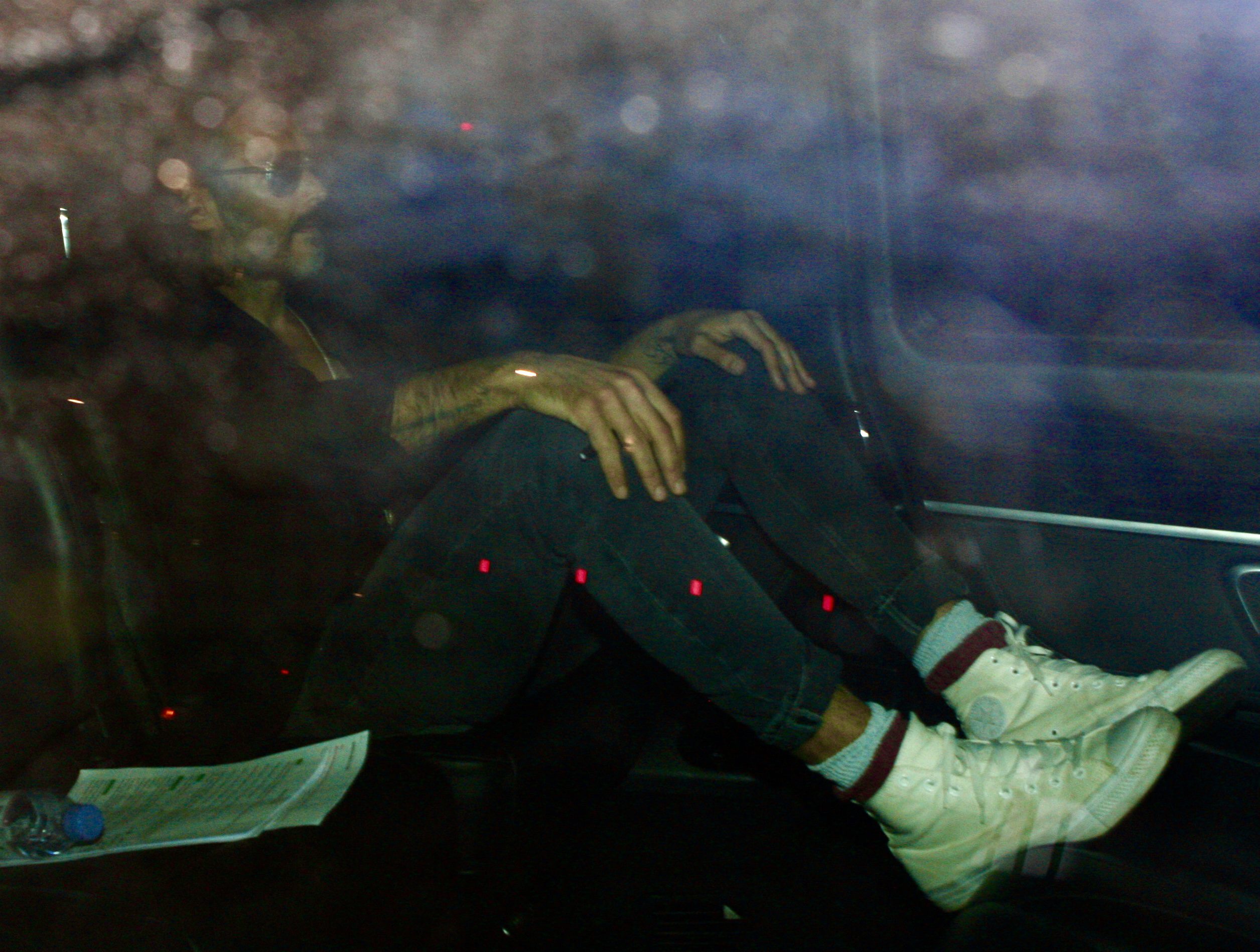 Russell Brand sits in a taxi with his hands on his knees