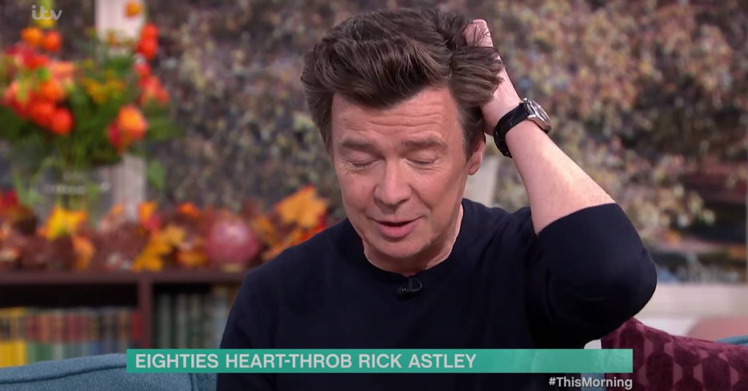 Rick Astley puts his hand in his hair