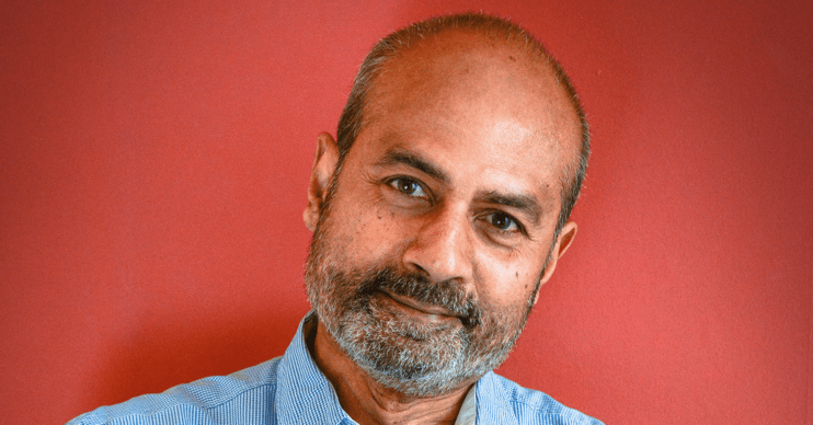 George Alagiah smiling against a red background