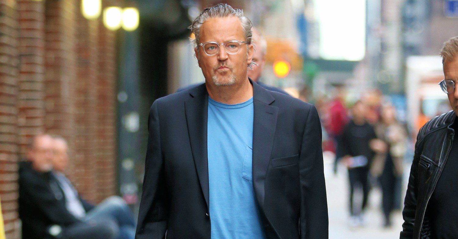Actor Matthew Perry walking down the street in a blue t-shirt and dark blazer