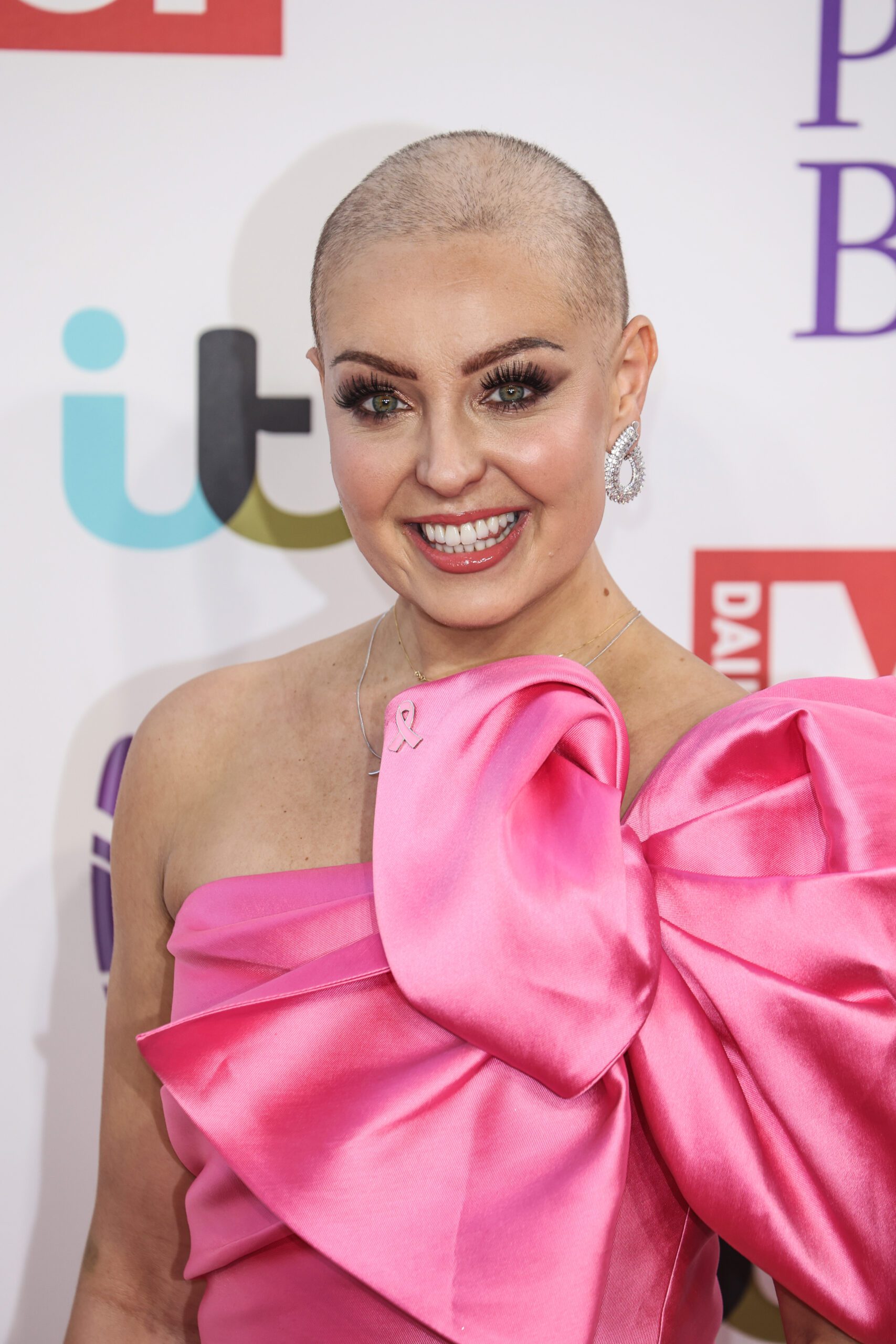 Amy Dowden without her wig wearing a pink dress with big bow