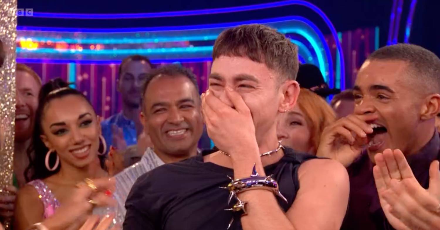 Olly Alexander covers his mouth with his hand