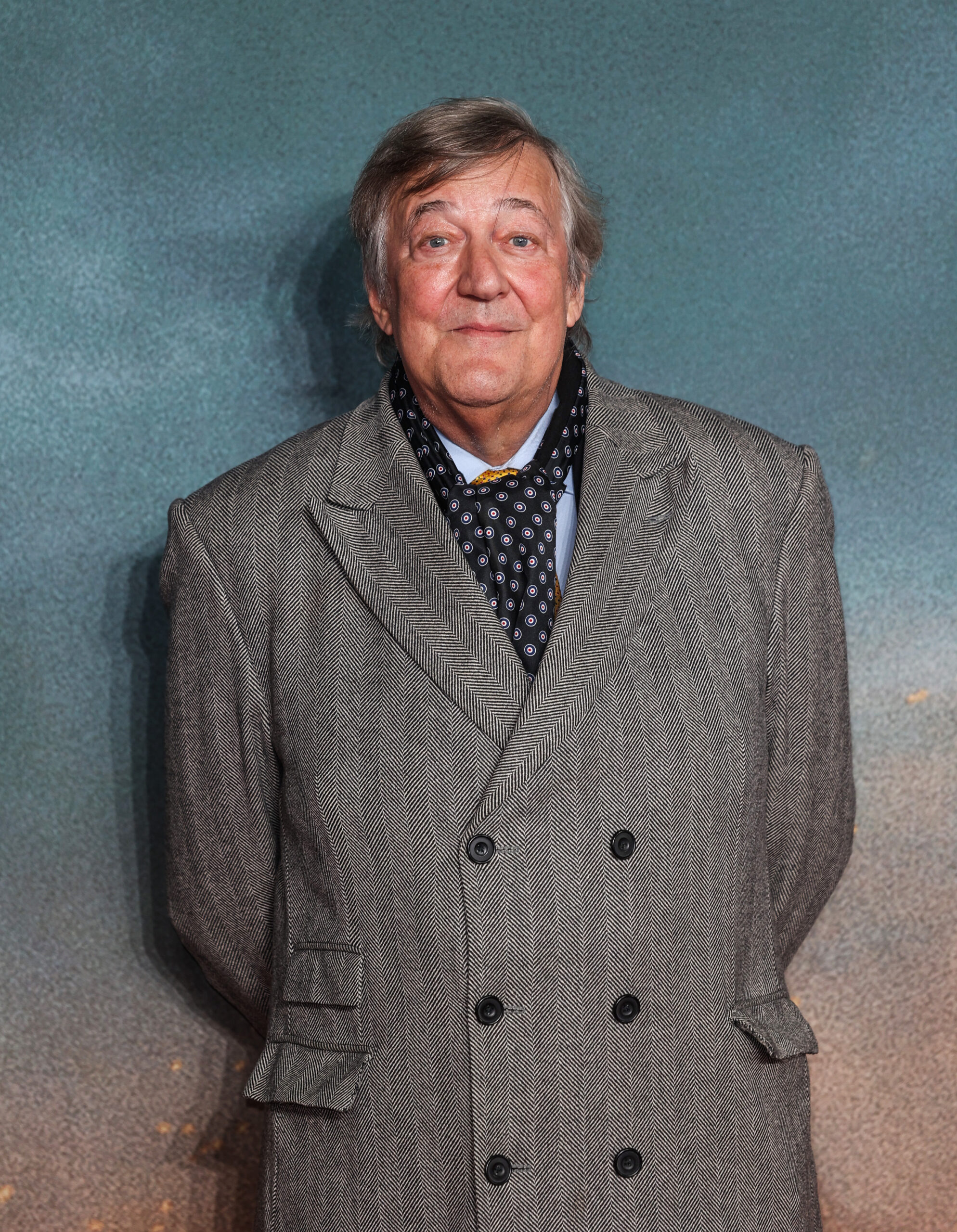 Stephen Fry smiling in a tweed coat