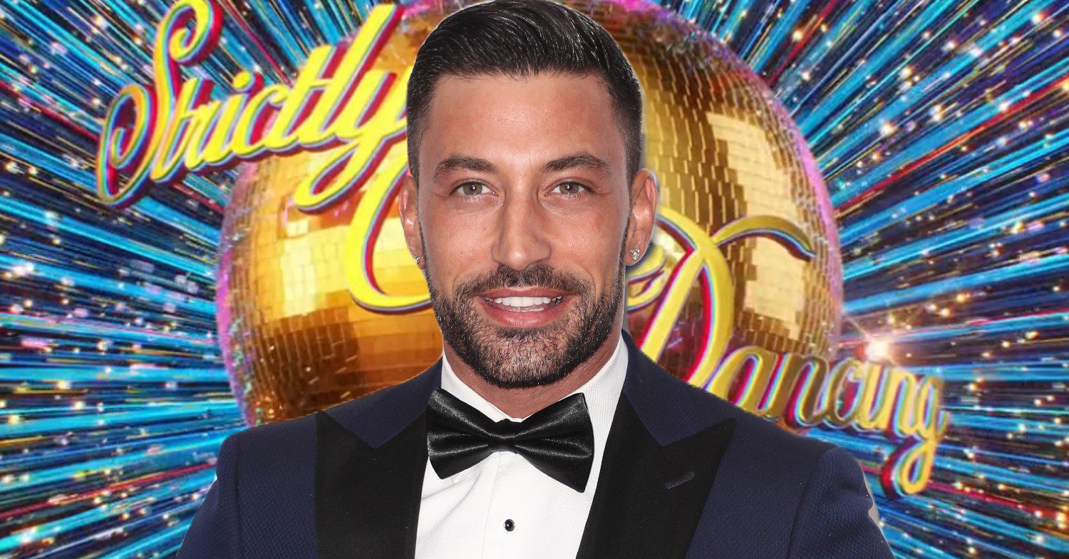 Giovanni Pernice in suit in front of Strictly logo
