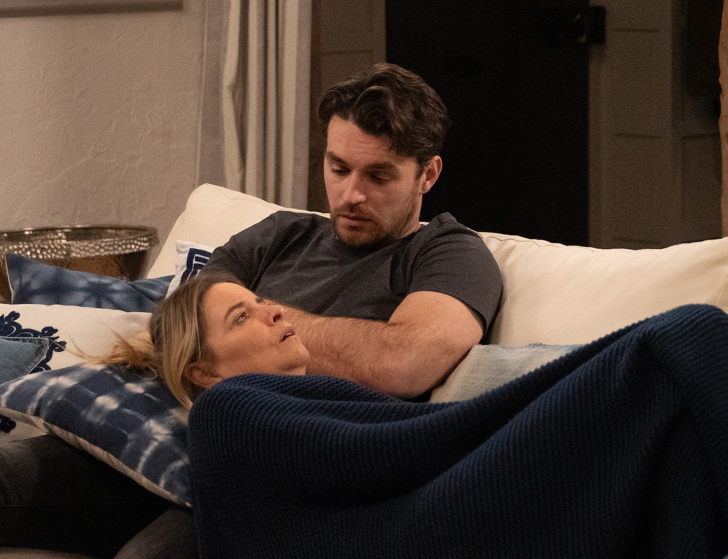 Emmerdale's Charity is lying on Mack's lap on the sofa