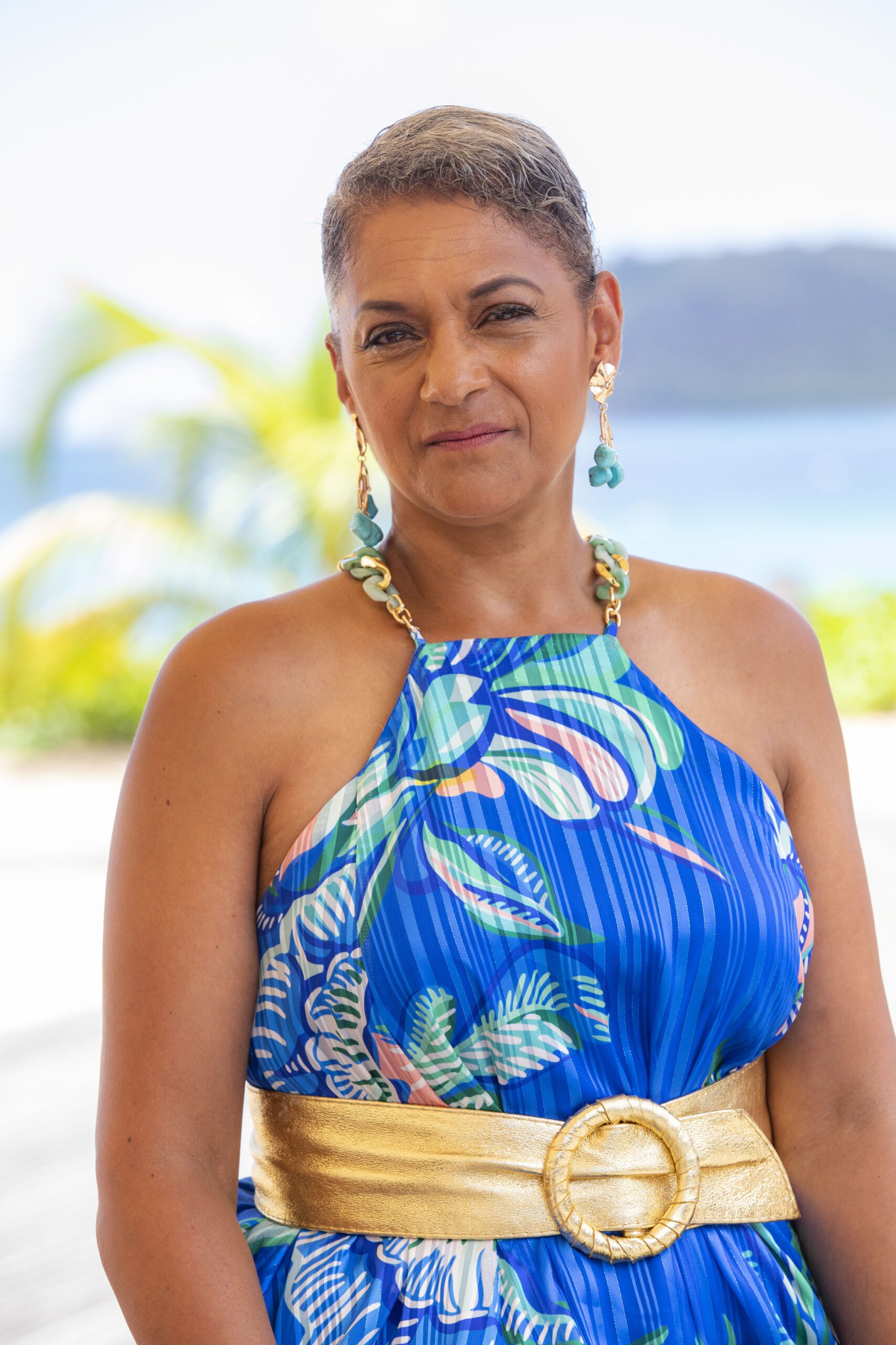 Cathy Tyson in floral blue dress as Jacqueline StClair in Death in Paradise
