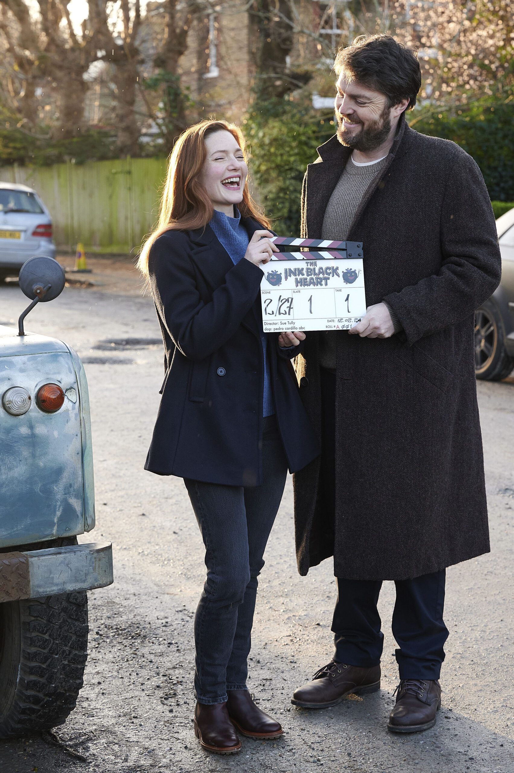 Holliday Grainger and Tom Burke laughing with each other on the set of the new Strike season The Ink Black Heart