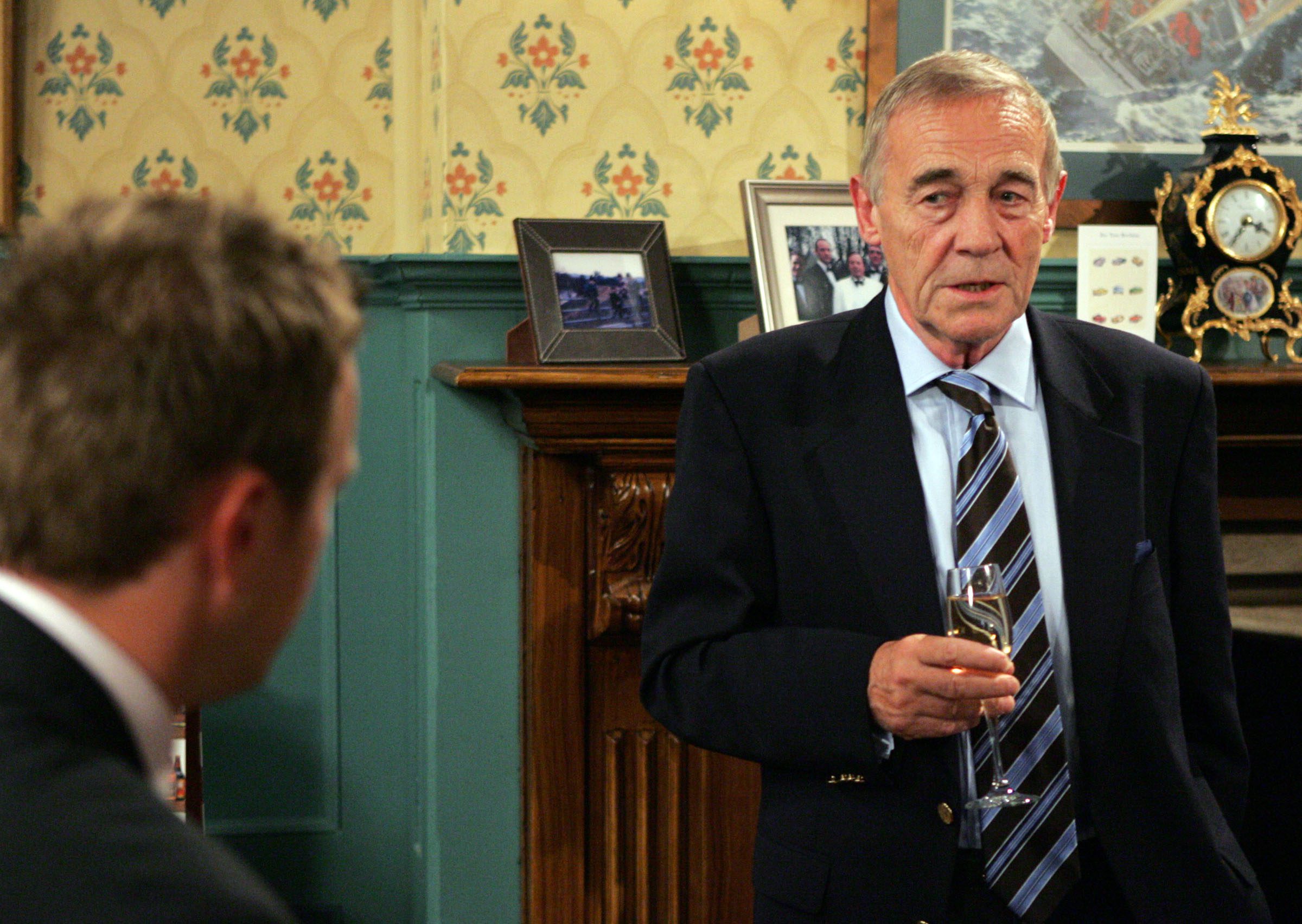 Emmerdale's Donald De Souza has a glass in his hand