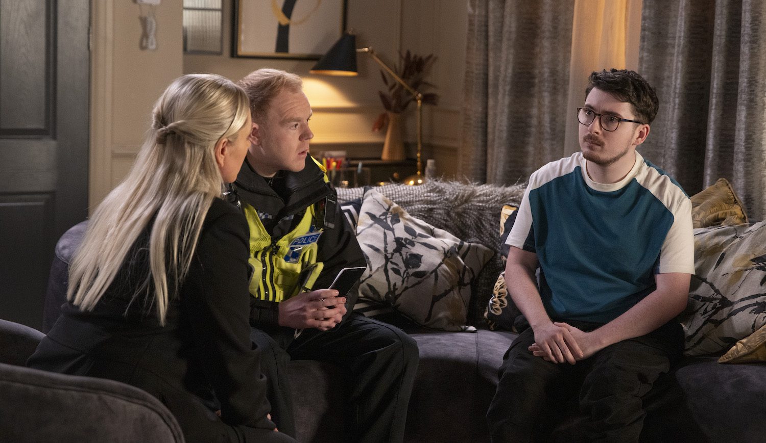 Coronation Street's DS Swain, PC Tinker and Bobby are talking on the sofa
