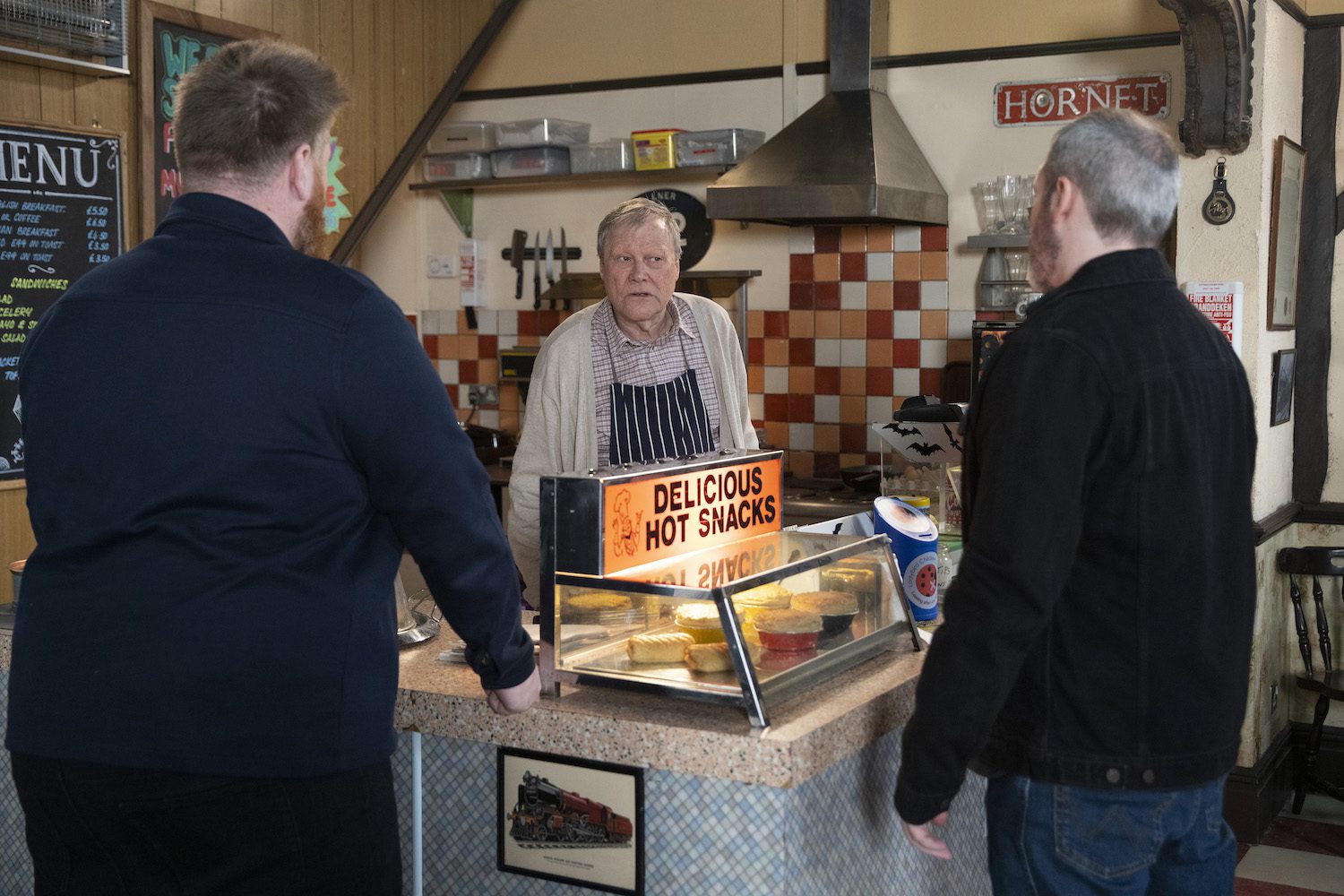Roy Cropper looks worried as two dodgy men approach the cafe counter