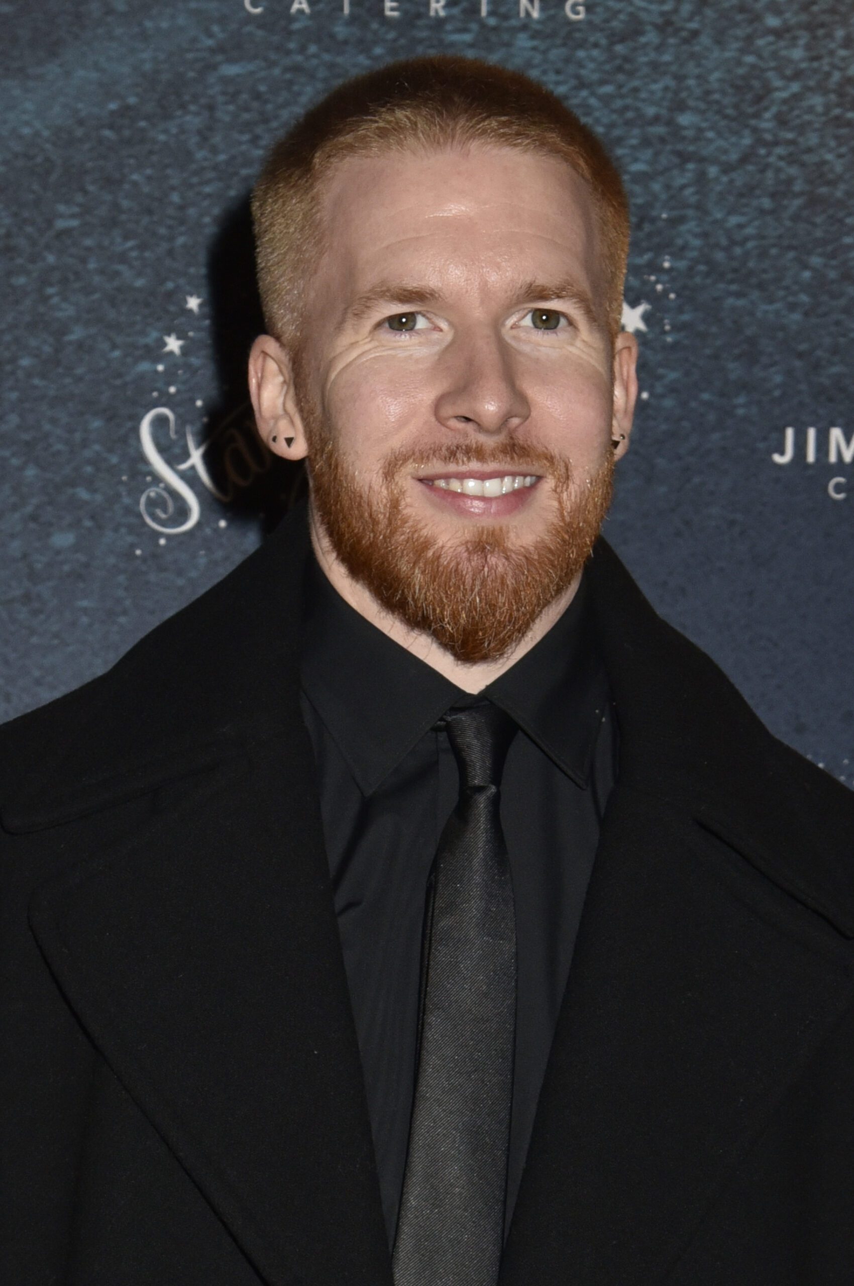 Neil Jones wearing a black suit and tie