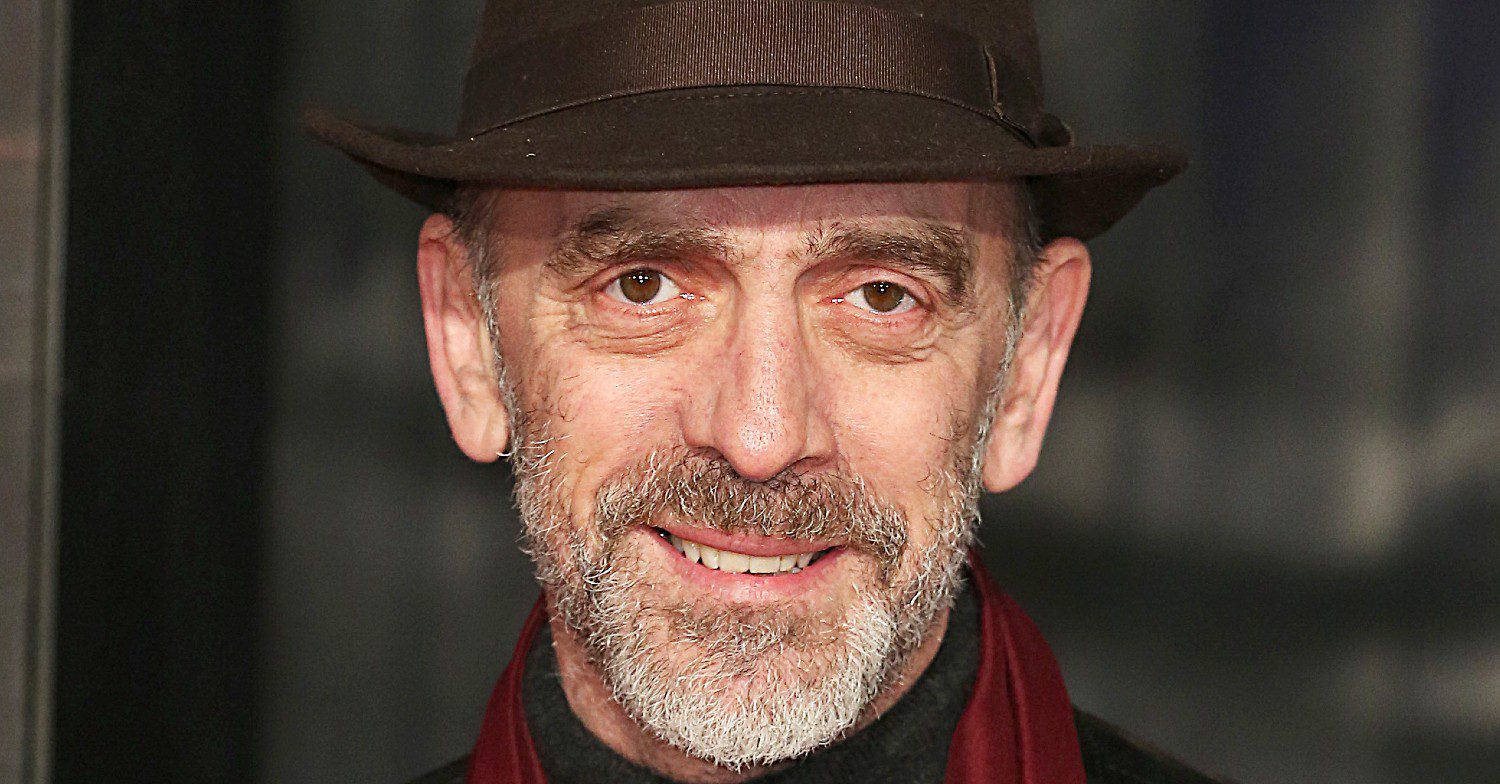 Adrian Schiller smiling in a hat