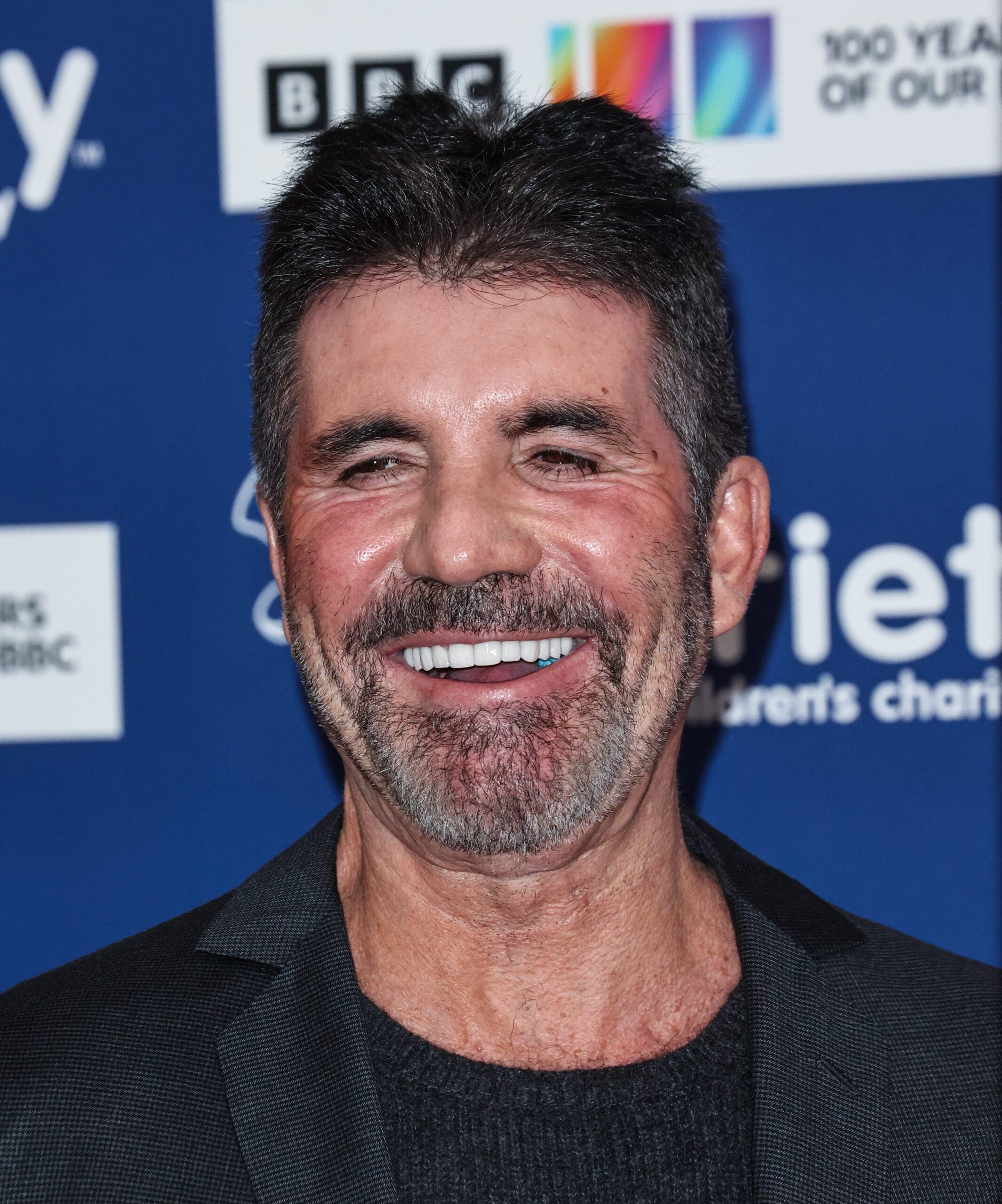 Simon Cowell smiling on red carpet wearing suit
