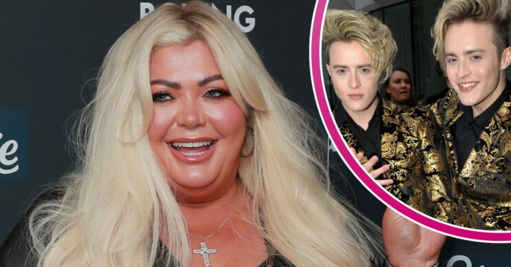 Gemma Collins in all black outfit showing peace sign and smiling with cut-out of Jedward posing in matching gold outfits