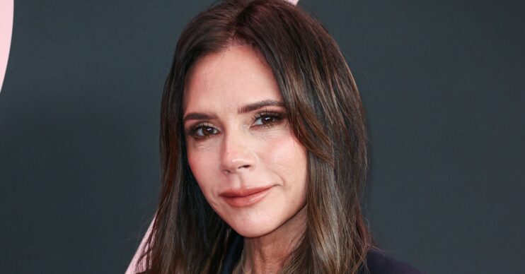 Victoria Beckham smiling at the camera on the red carpet with long brunette hair