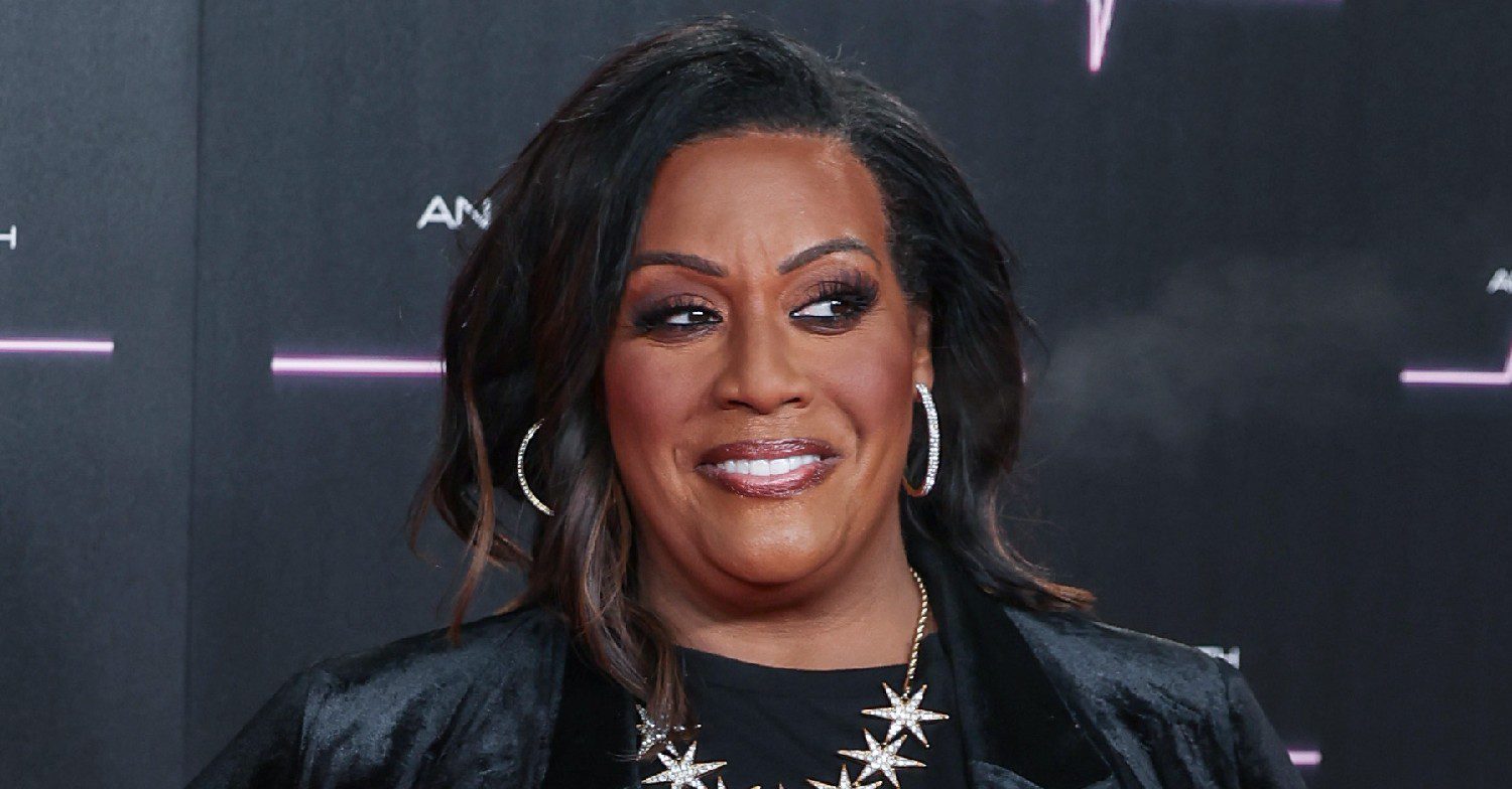 Alison Hammond smiling at a red carpet event, wearing black on a black background