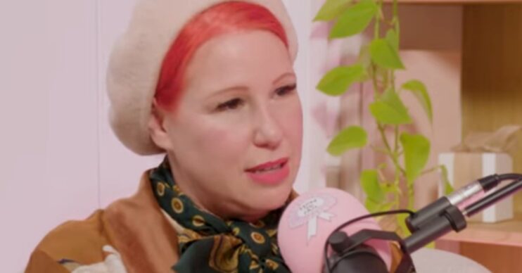 Angel Strawbridge frowning whilst wearing a beret on a pink podcast set, whilst chatting on Elizabeth Day's How to fail podcast