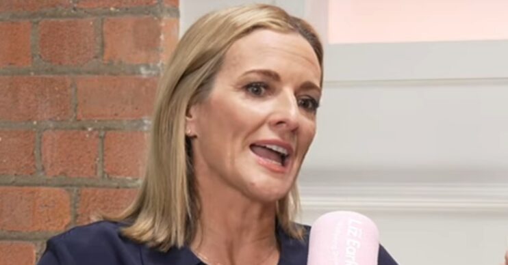 Gabby Logan wearing a dark blue blouse whilst talking into a microphone