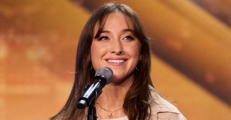 Sydnie Christmas smiling with a microphone in shot on BGT