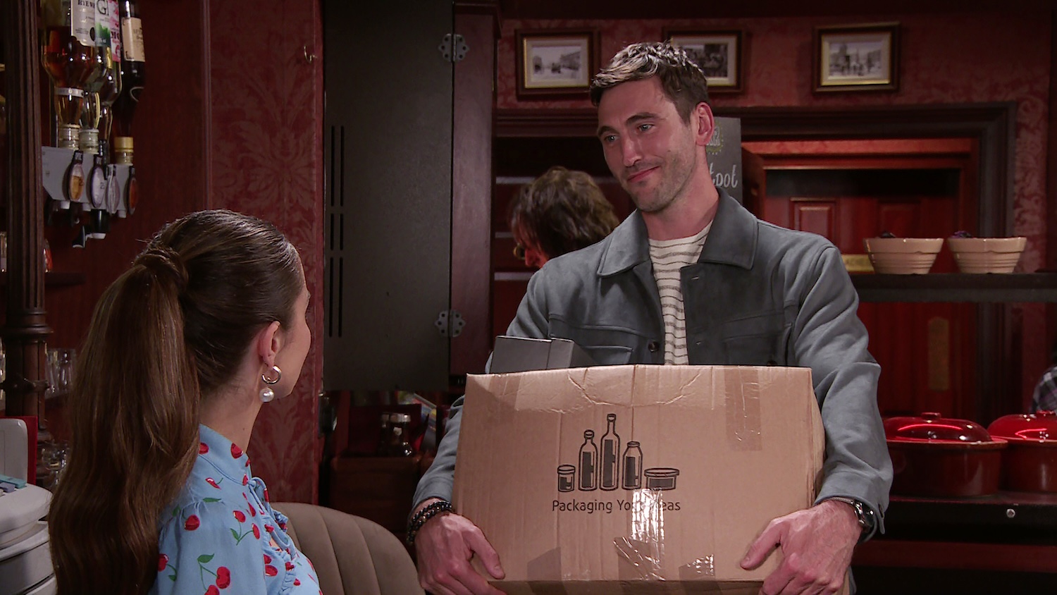 Kit talking to Daisy on Corrie with a box in his hands