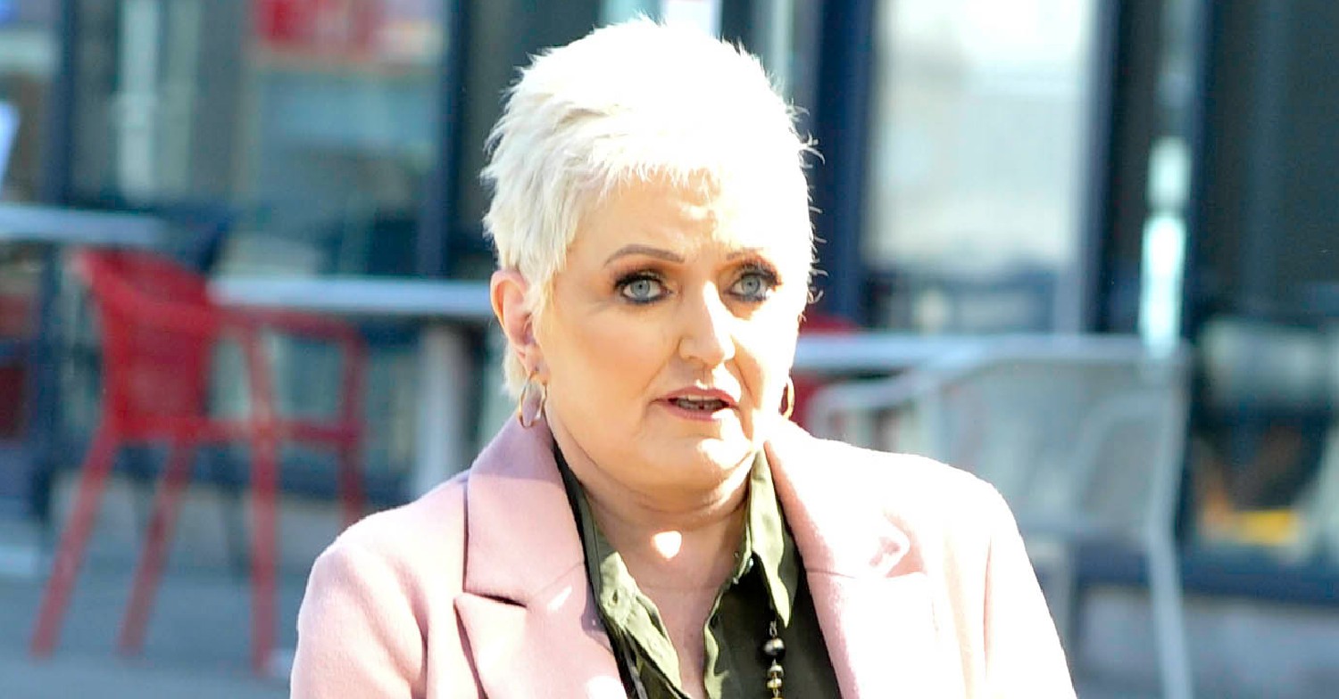Linda Nolan with serious expression in pink coat on outing