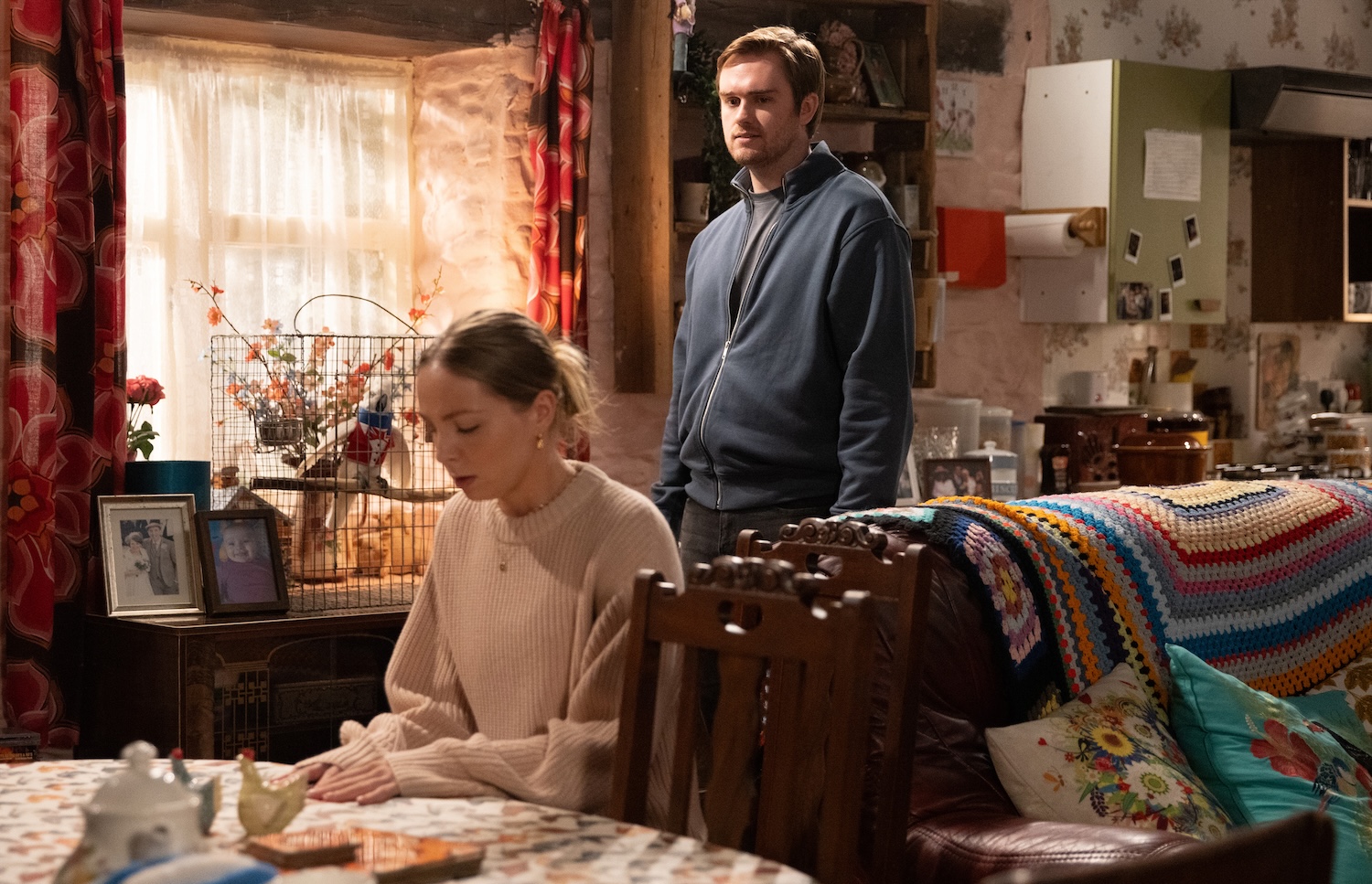 Tom standing behind Belle on Emmerdale