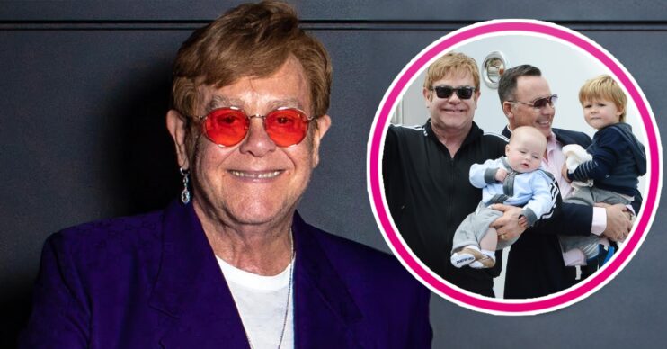 Elton John smiling alongside photo of his husband David and children