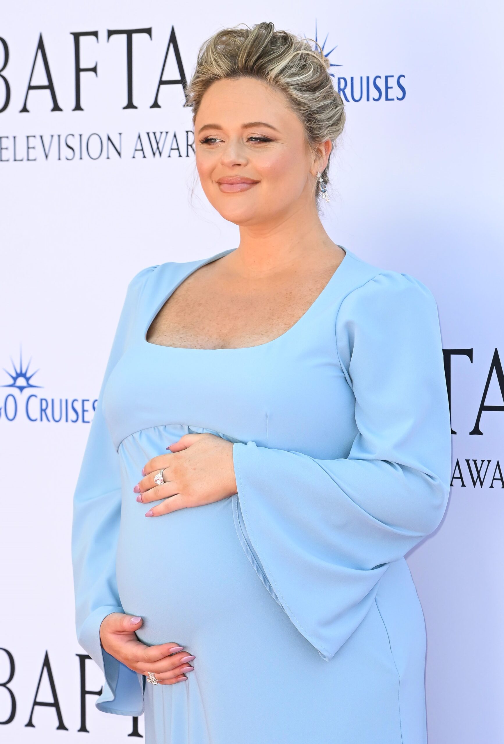 Emily Atack cradles baby bump in blue dress at the BAFTAs