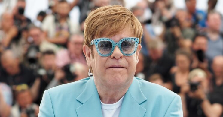 Elton John in blue blazer and glasses