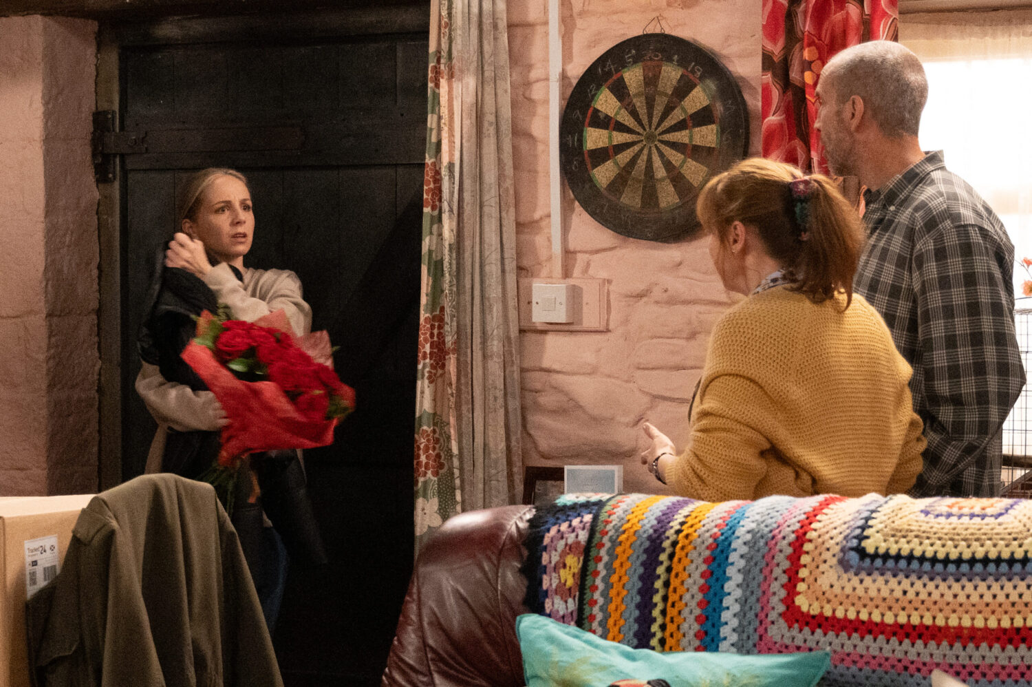 Belle holding flowers whilst speaking to Lydia and Sam