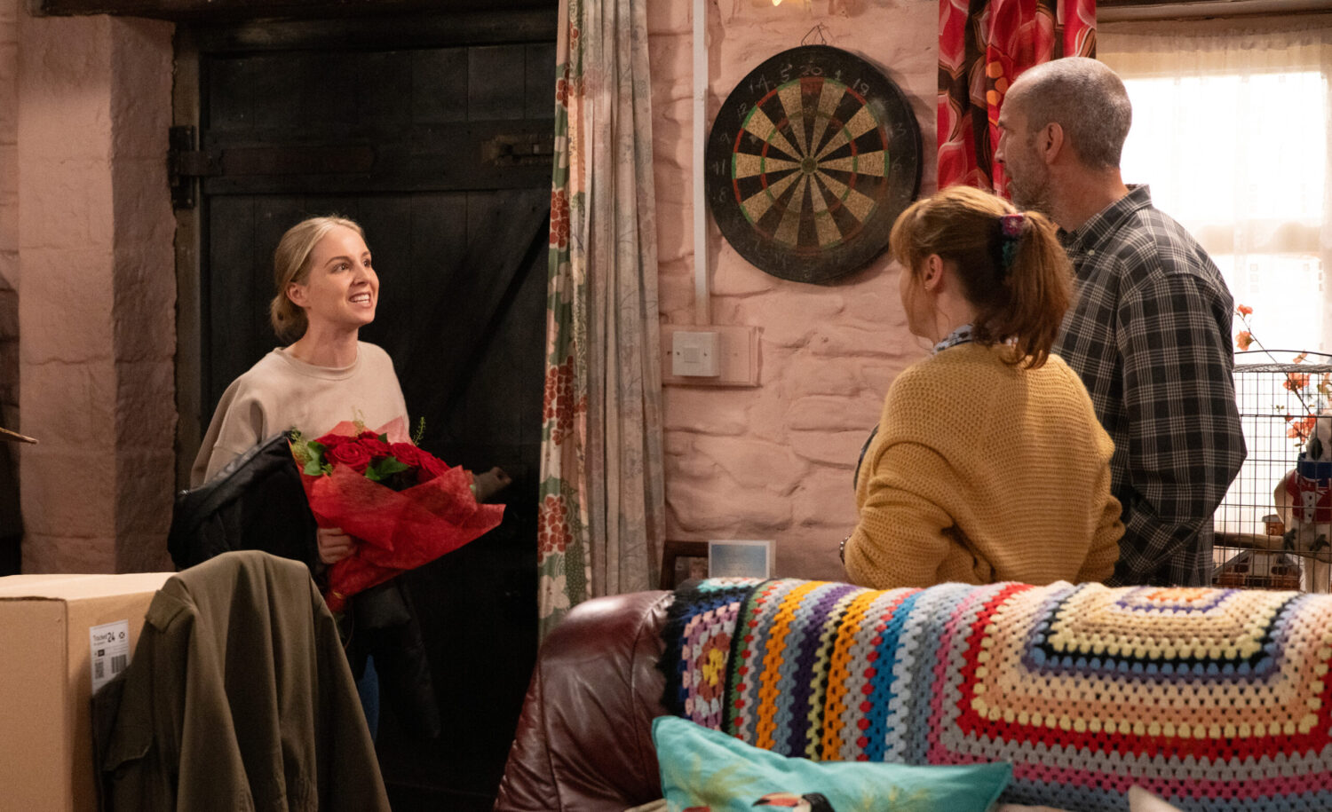 Belle holding flowers whilst speaking to Lydia and Sam