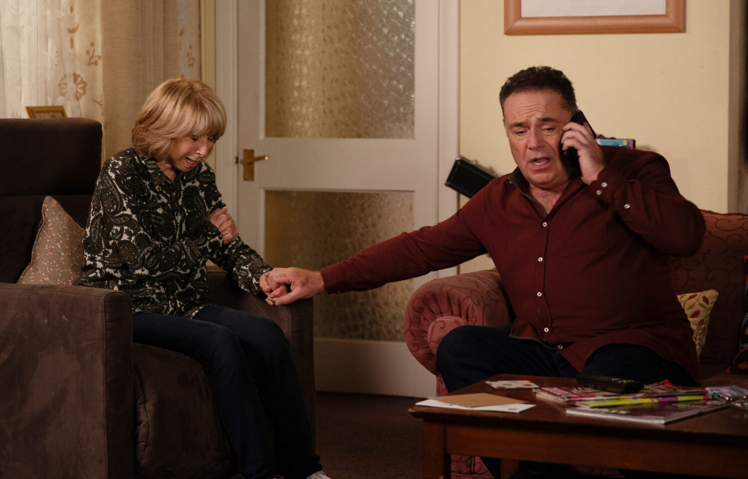 Jesse on the phone as Gail holds her arm in pain
