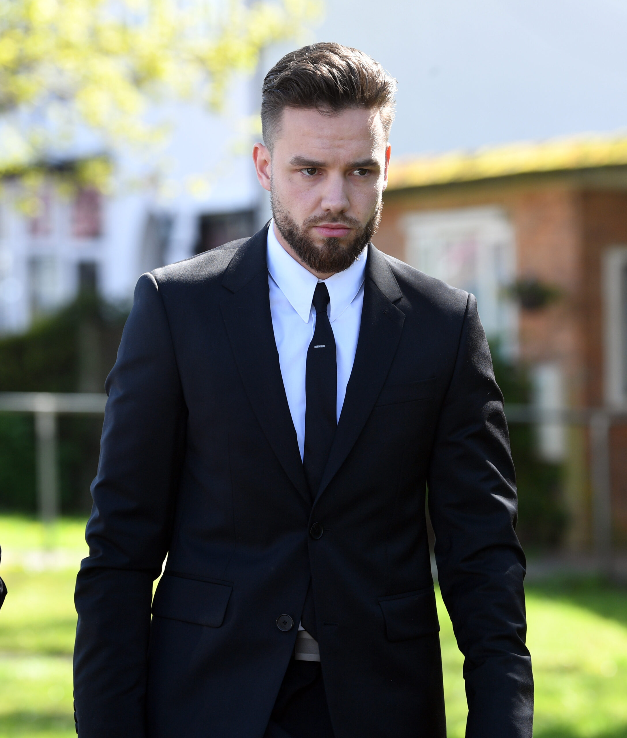 Liam Payne looking solemn in a black suit