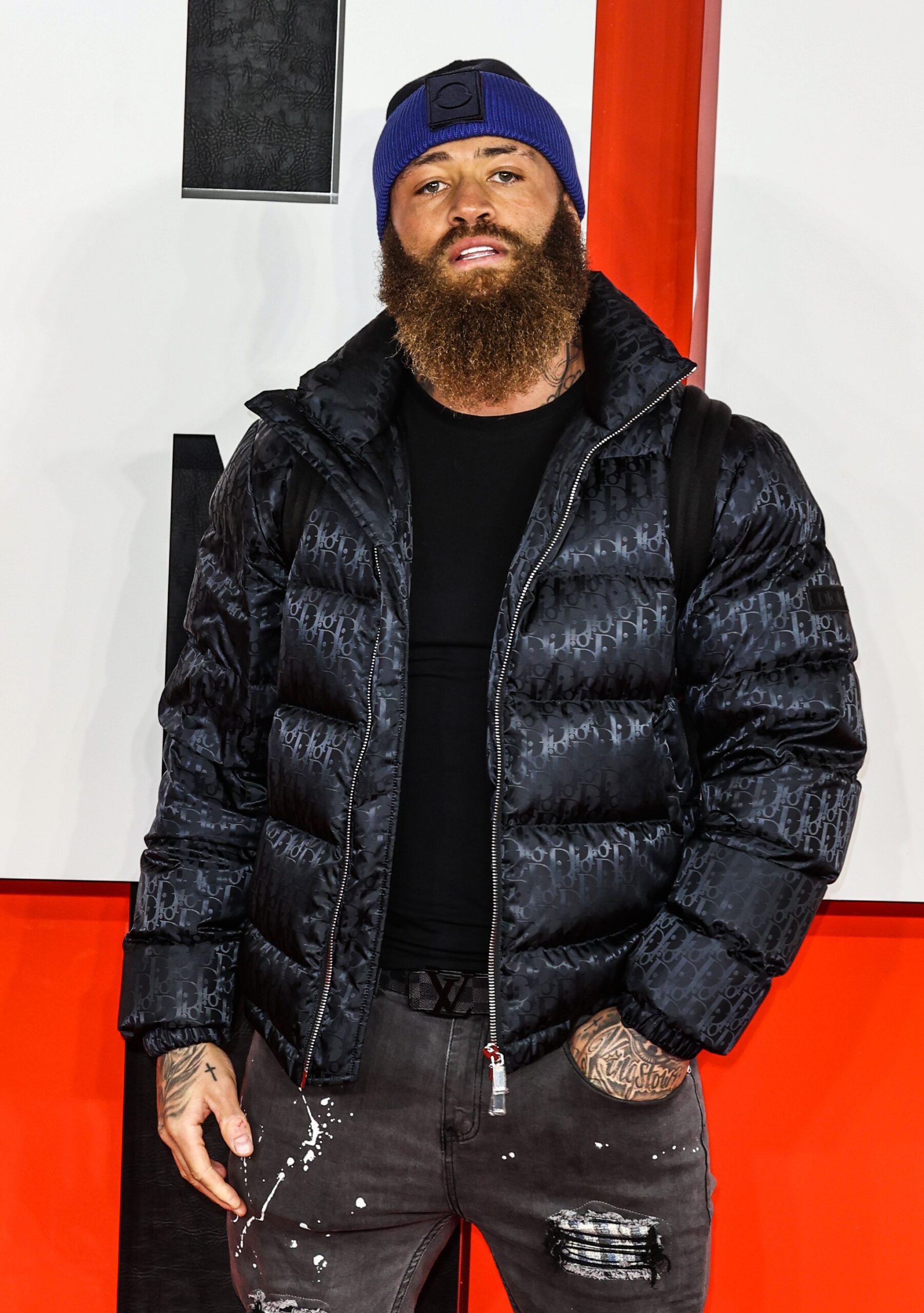 Ashley Cain posing in black coat at event