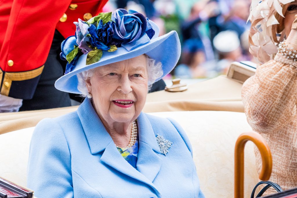 The Queen smiling in light blue outfit during carriage procession
