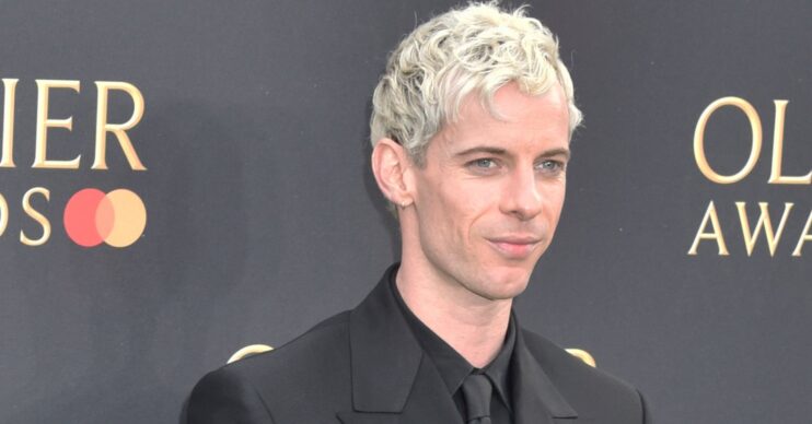 Luke Treadaway in a black suit smiling