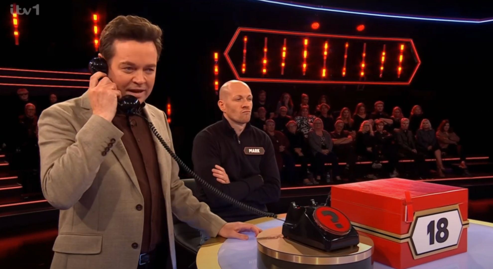 Stephen Mulhern on the phone to the banker on Deal or No Deal beside contestant Mark