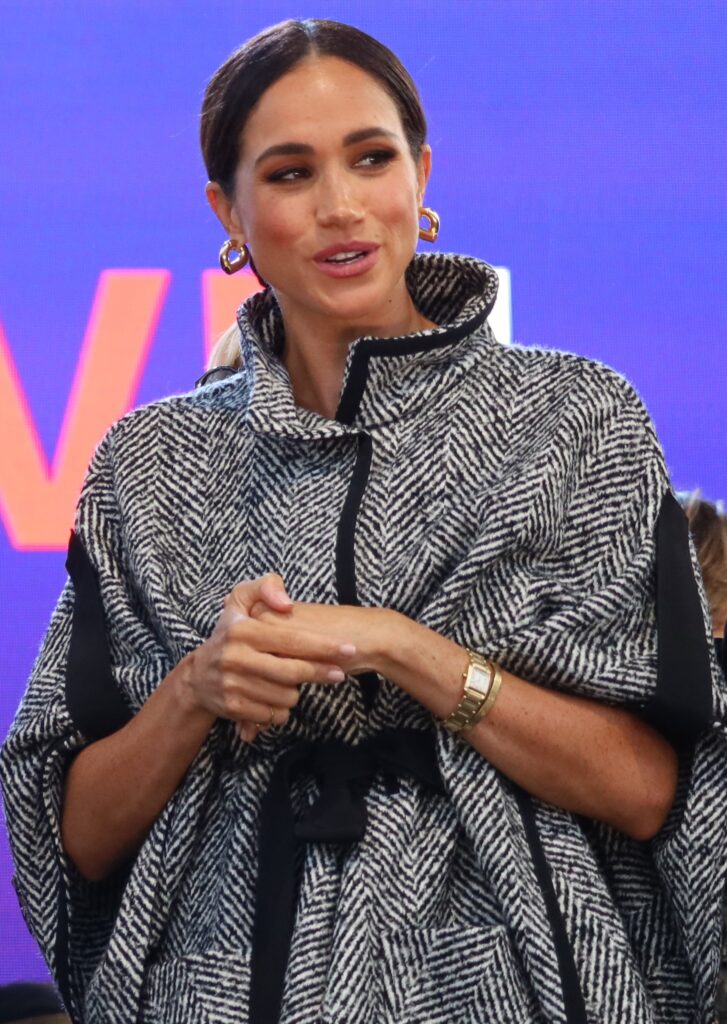 Meghan Markle holding her hands in grey coat at visit