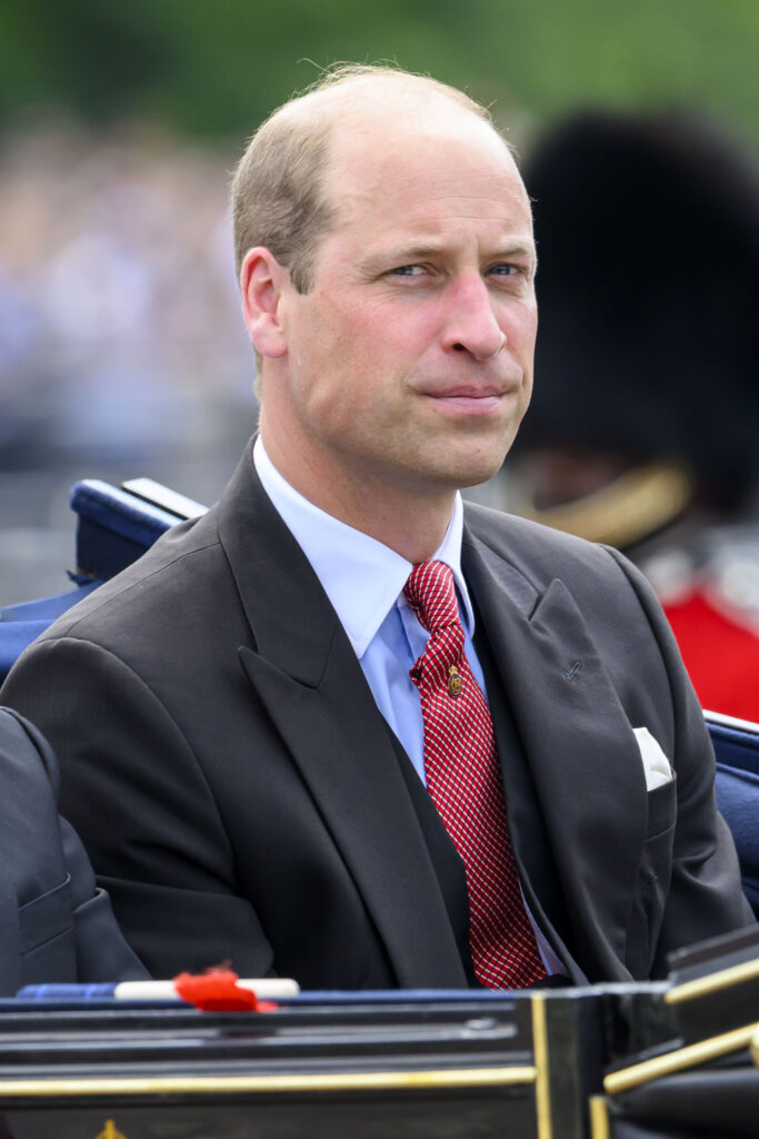 Prince William looking serious in suit whilst riding in carriage
