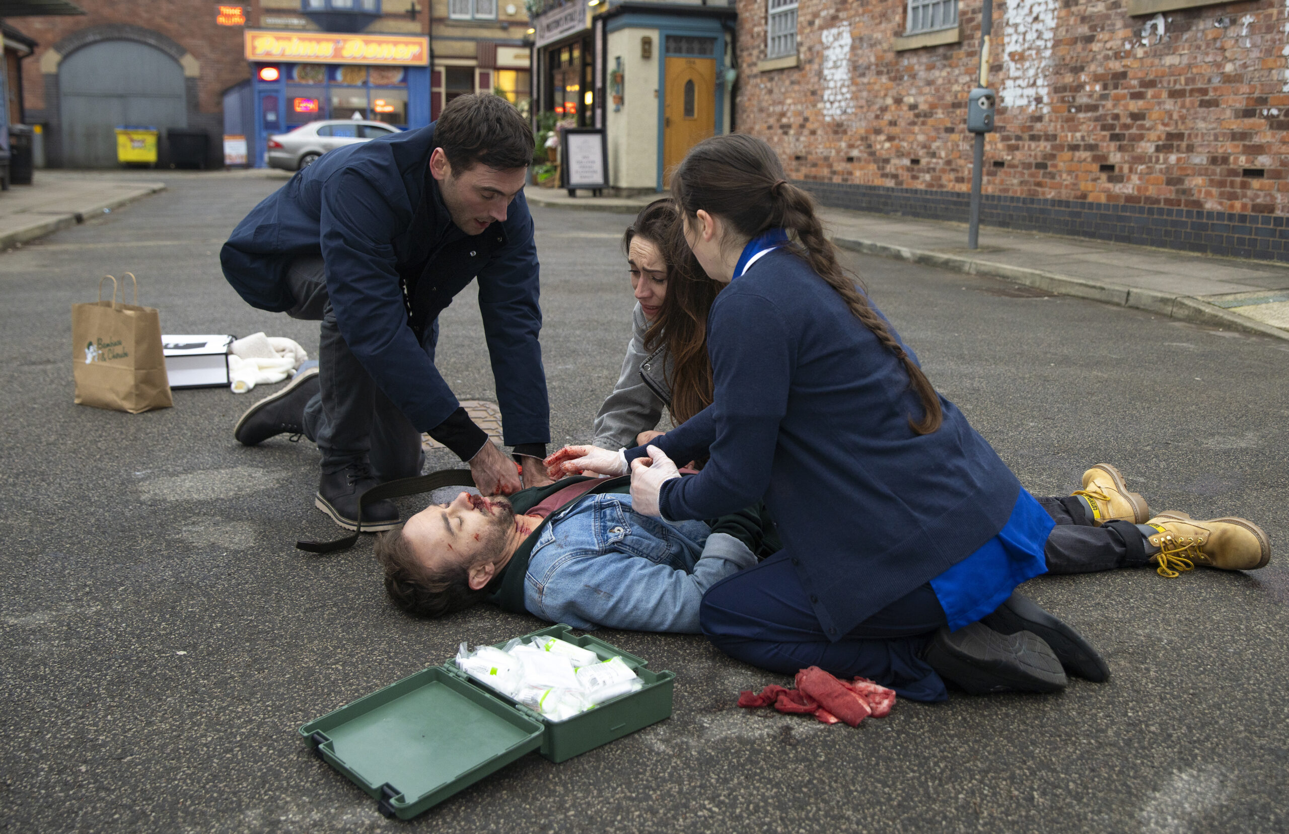 Coronation Street's Kit and Shona tending to injured David on the Street