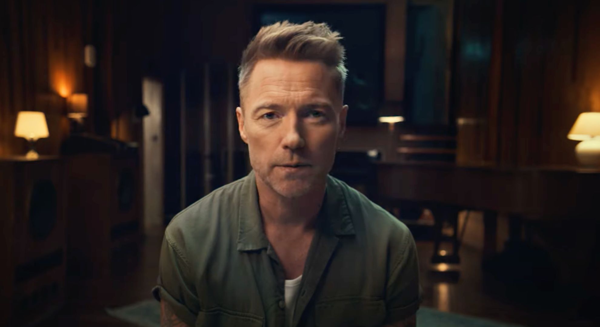 Ronan Keating wears a green shirt and sits on a chair