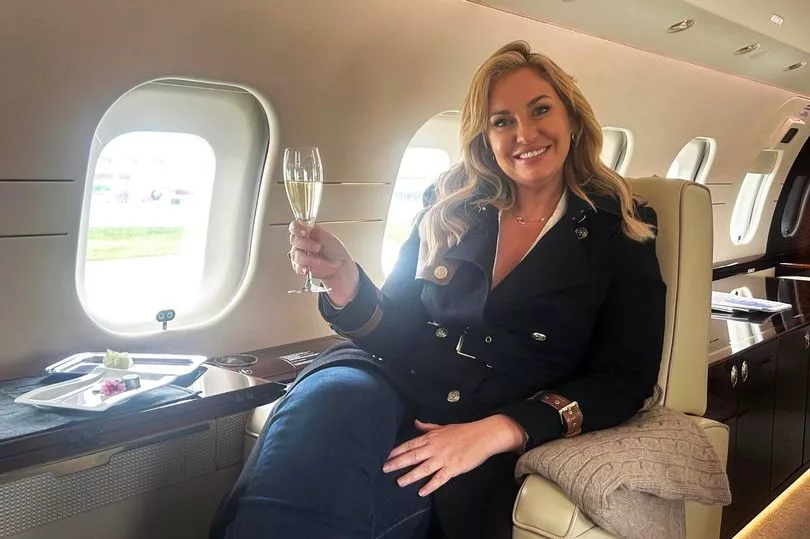 Josie Gibson smiling on a private jet with a glass of champagne