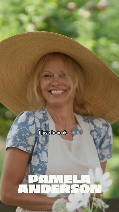 Pamela Anderson smiling in a straw hat