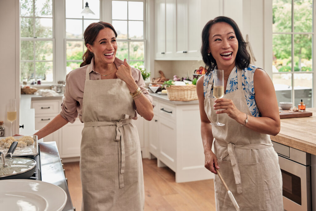Meghan Markle smiles as she cooks in the kitchen