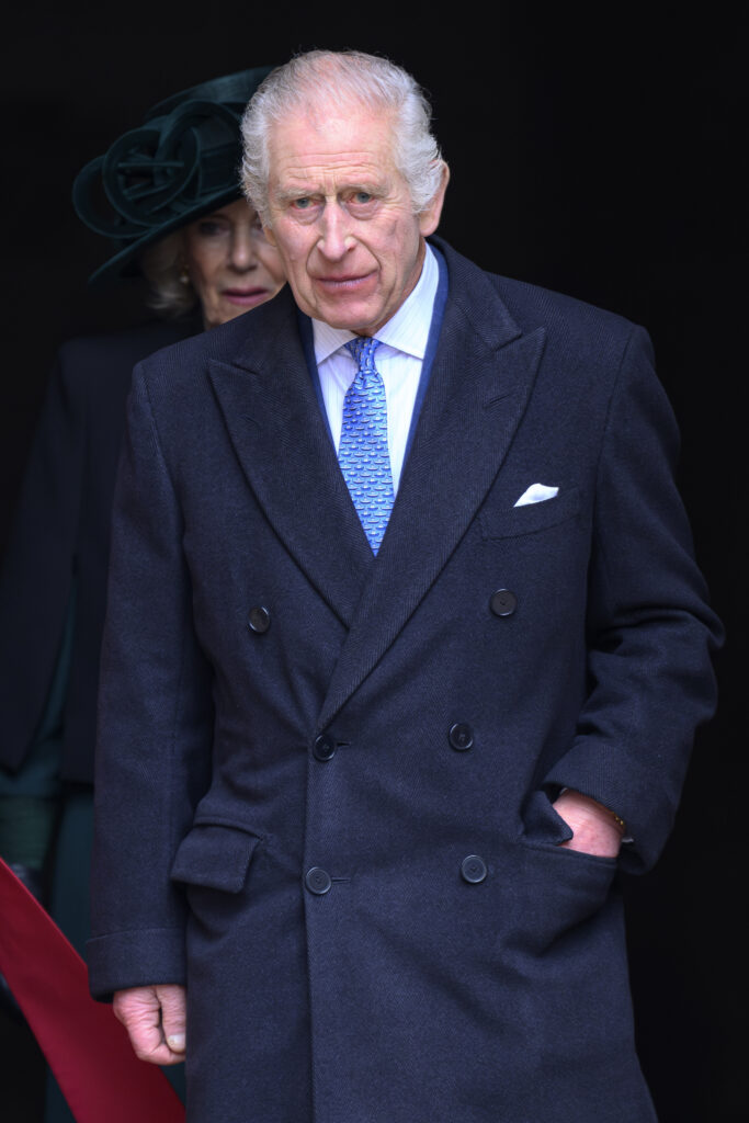 King Charles wears a dark navy coat over a suit jacket