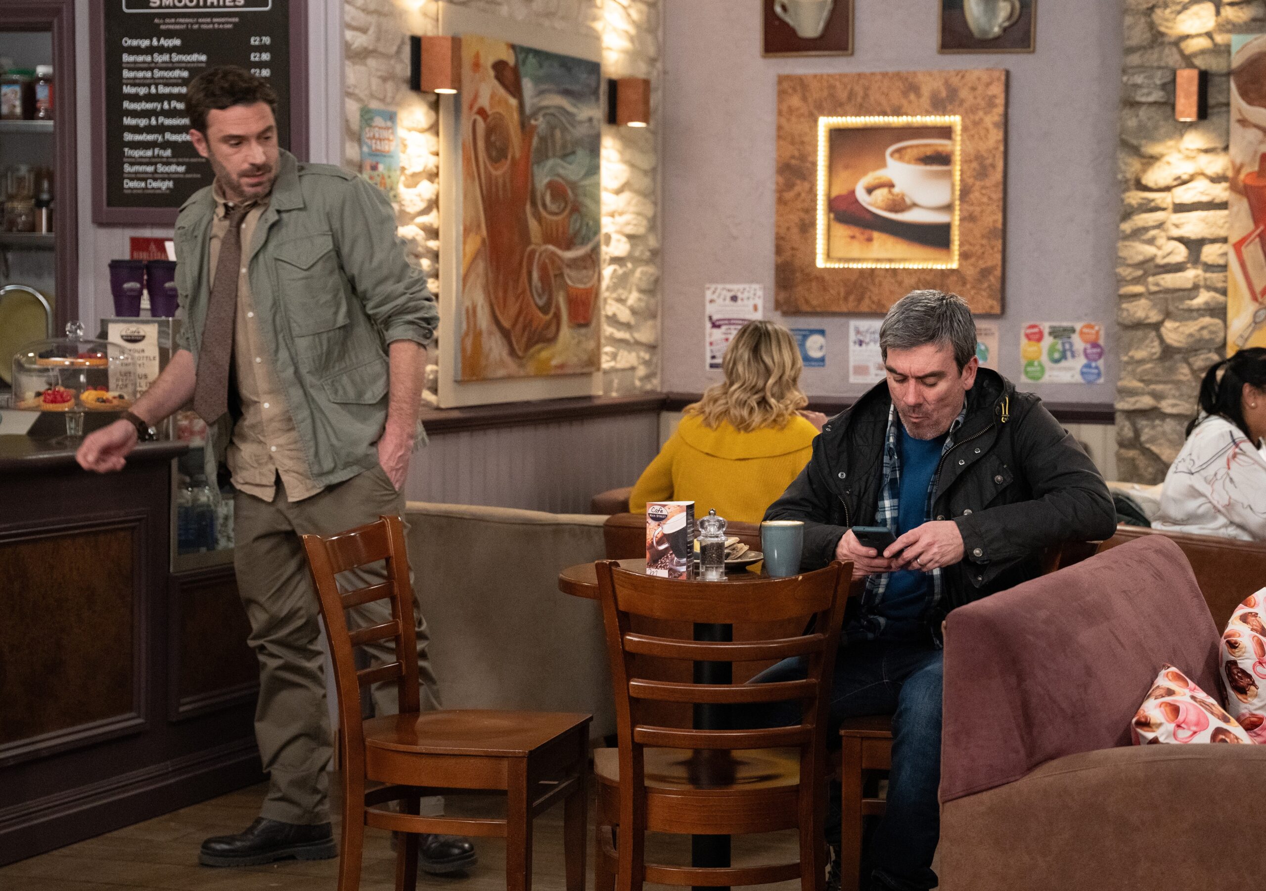 John staring at Cain on phone in Emmerdale